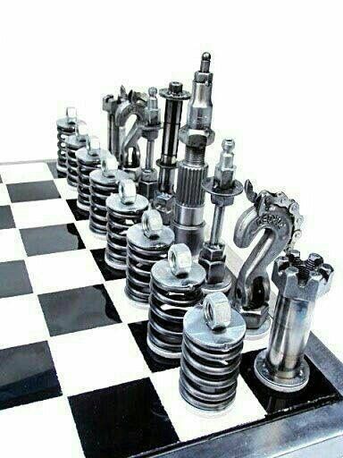 a chess board with many metal pieces on it and black and white checkered floor