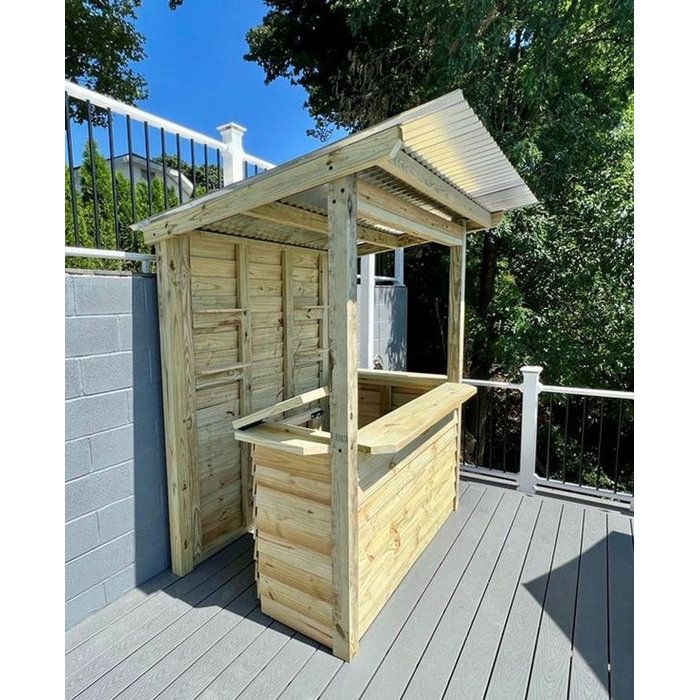 a small wooden bar on a deck with trees in the background