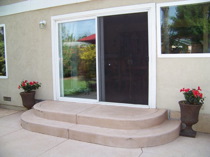 two flower pots are sitting on the steps in front of a house with glass doors