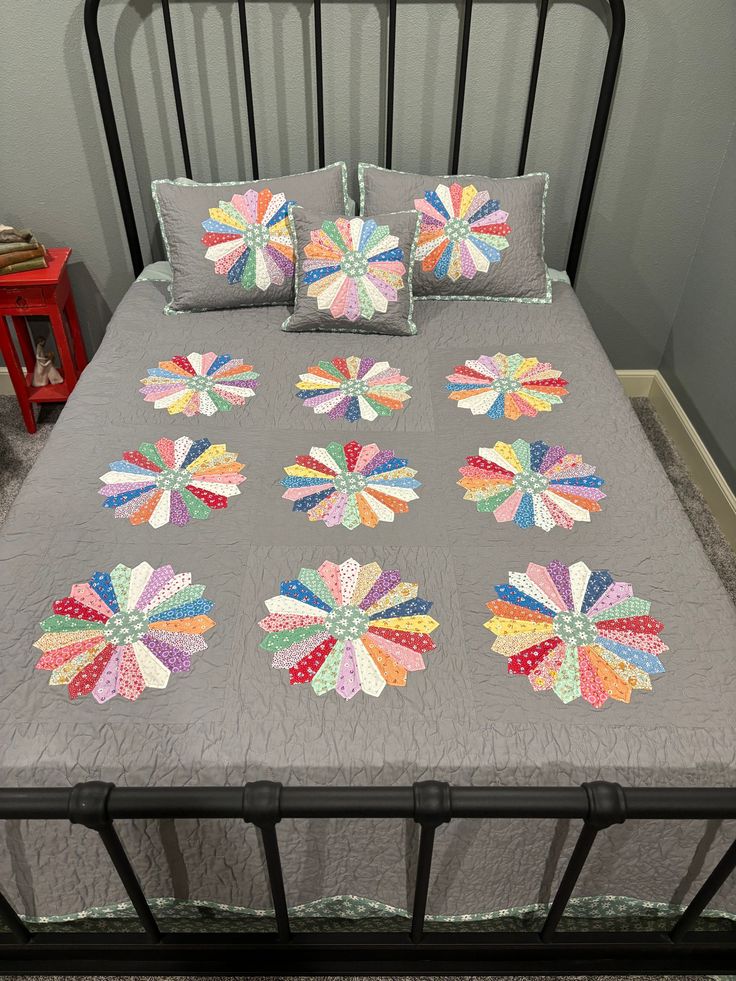 a bed with pillows and quilts on it in a room next to a red table