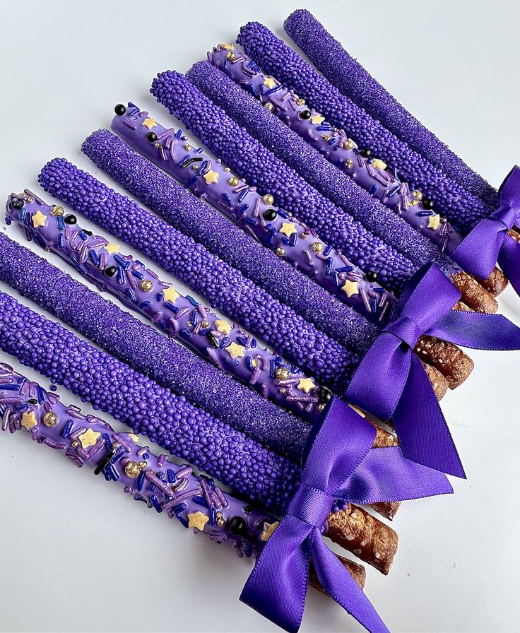 purple candy sticks with gold and blue decorations on them, tied together by a purple ribbon