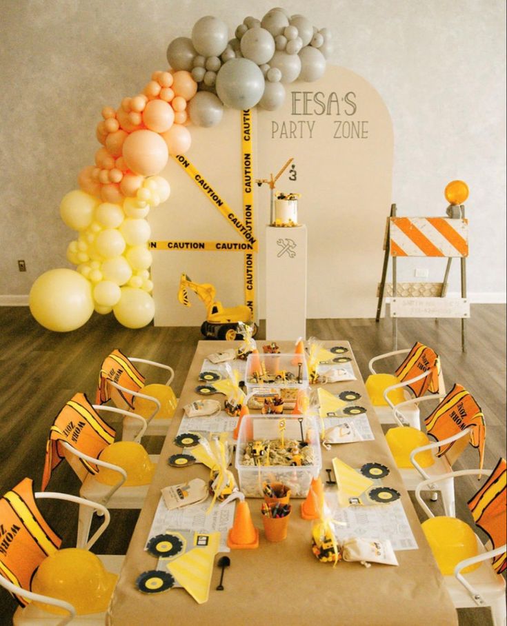 a table with construction themed decorations and balloons