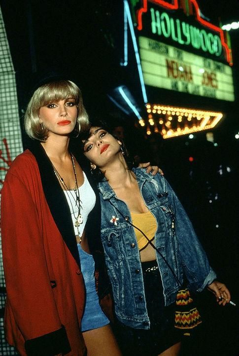 two young women standing next to each other in front of a hollywood marquee