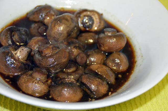 a white bowl filled with cooked mushrooms and sauce on top of a yellow table cloth