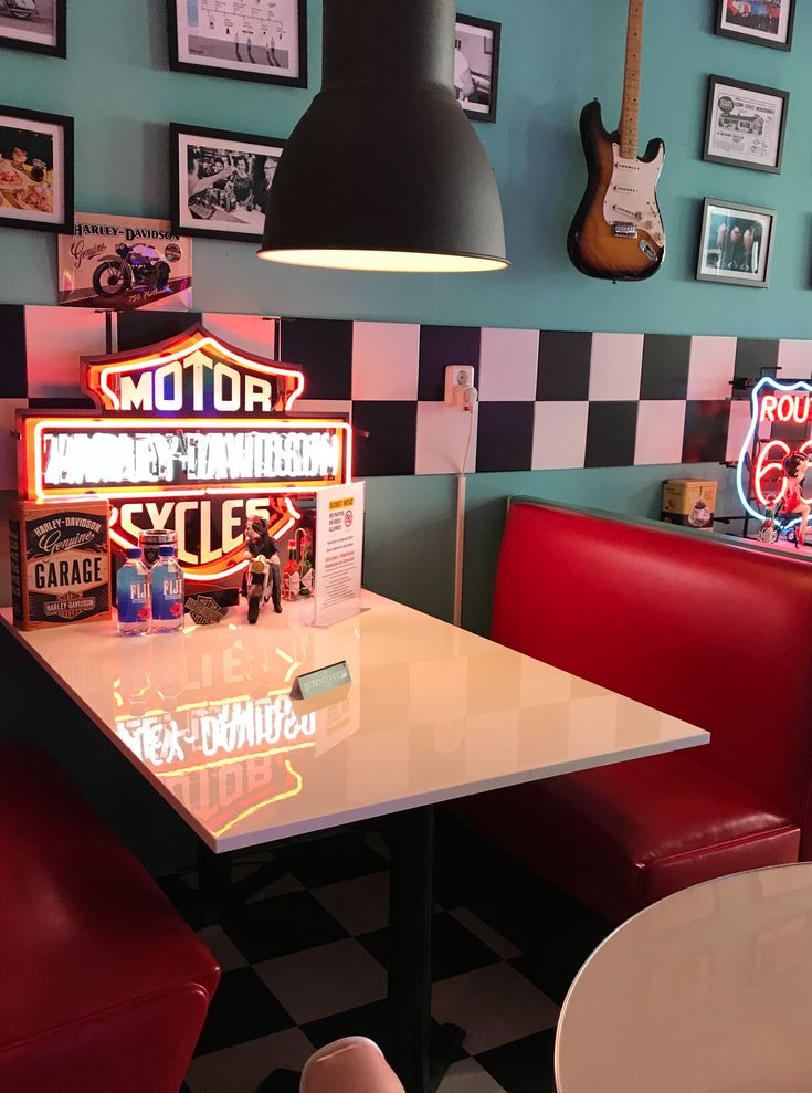 a restaurant with checkered walls and neon signs on the wall, along with red booths