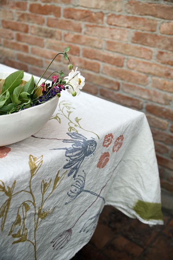 a bowl filled with flowers sitting on top of a table next to a brick wall