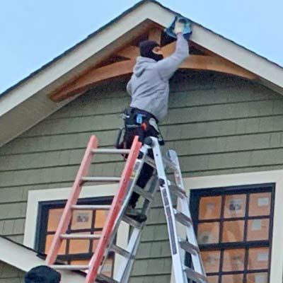 a man on a ladder painting the side of a house