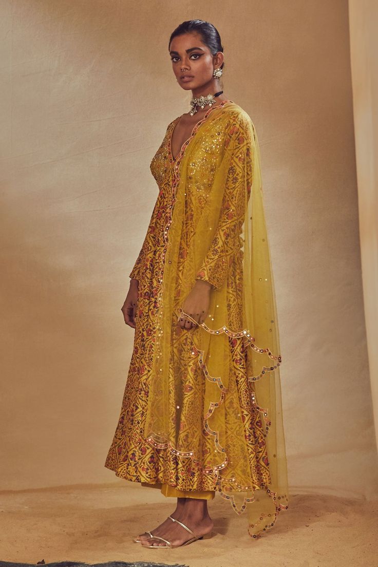 Yellow anarkali with floral print and embroidery on the yoke. Comes with straight pants and net dupatta.
Component: 3
Pattern: Print and Embroidery
Type Of Work: Floral Print, Dori Work, Mirrors, Anchor Threads, Sequins and Zardozi
Neckline: V neck
Sleeve Type: Full
Fabric: Dupion Silk and Net
Color: Yellow
Other Details: 
Dupatta with scallop border
Low back with tie up and tassels
Note: The purple kurta set worn by the male model is not for sale
Occasion: Sangeet - Aza Fashions V Neck Anarkali, Floral Print Anarkali, Anarkali Tops, Yellow Anarkali, Anarkali Churidar, Dori Work, Designer Anarkali Dresses, Anchor Threads, Scallop Border