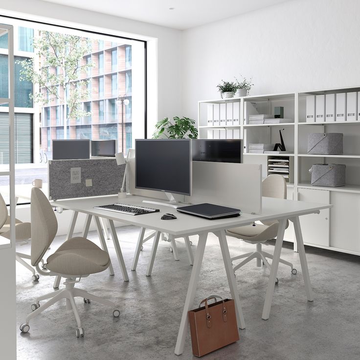 an office with multiple desks and chairs in front of large windows, all white