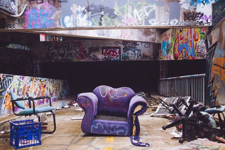 an abandoned building with graffiti all over the walls and floor, including a purple chair