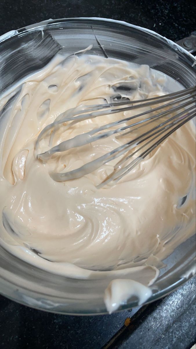 a bowl filled with cream and whisks on top of a table