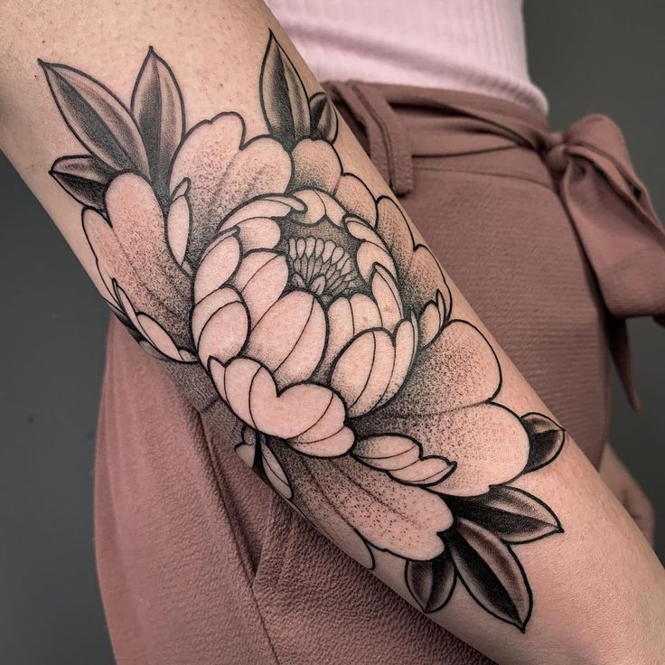 a black and white flower tattoo on the arm