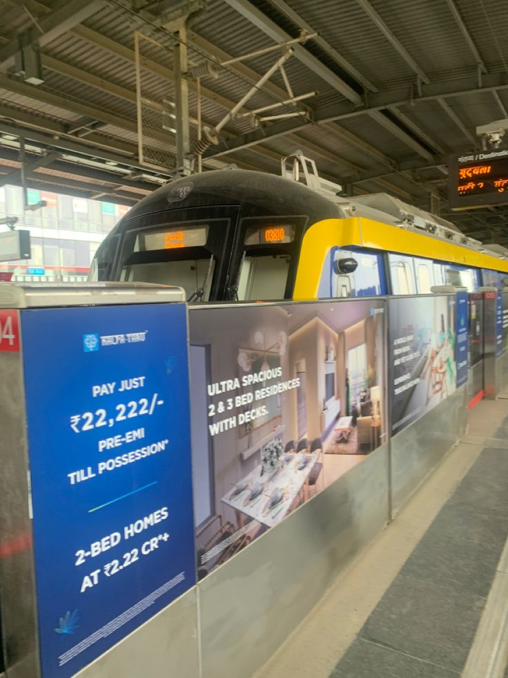 a yellow and blue train parked in a station next to a sign that reads pay just $ 22 22 / hour