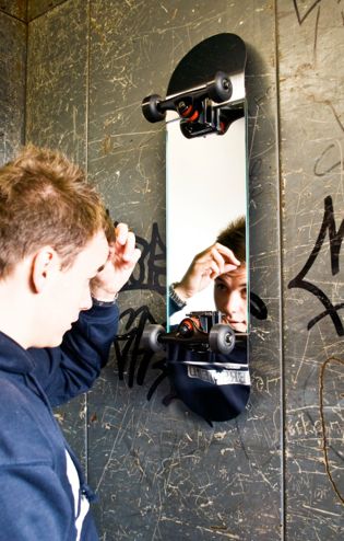 a man looking at himself in the mirror with graffiti on the wall behind him,