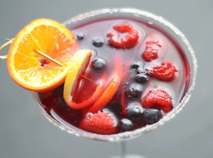 a close up of a drink in a glass with fruit garnish on the rim