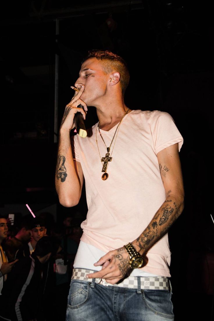 a man with tattoos on his arm singing into a microphone in front of a crowd