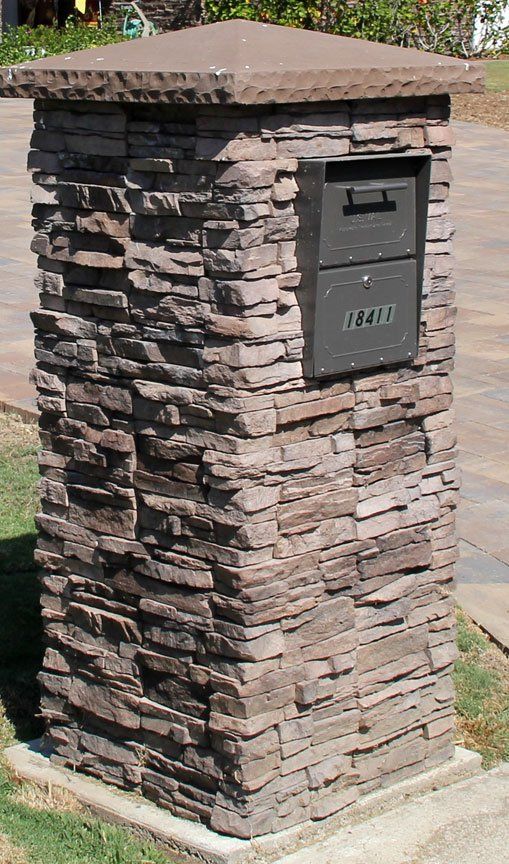 a stone mailbox sitting on the side of a road