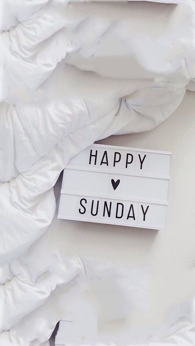 a white sign that says happy sunday on it's side next to a pile of pillows