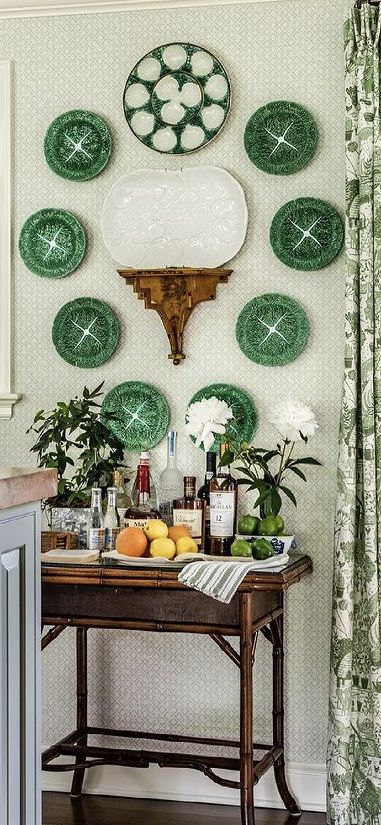 a table topped with plates and drinks next to a wall covered in green leaves on the wall