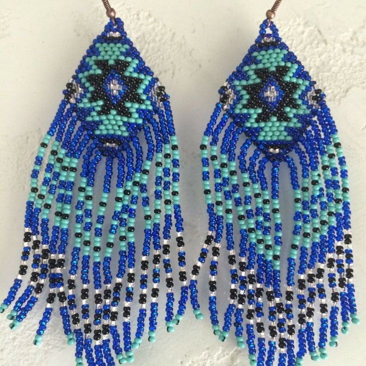 two pairs of blue and black beaded earrings on a white surface with beads hanging from them