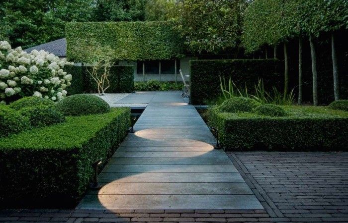 an outdoor walkway surrounded by hedges and trees