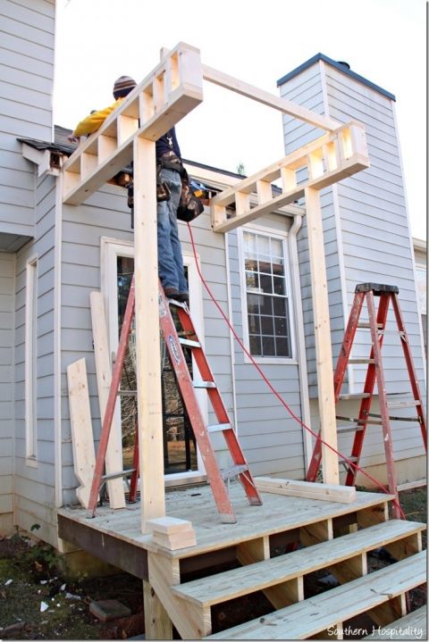 a man standing on top of a step ladder next to a house with windows and siding