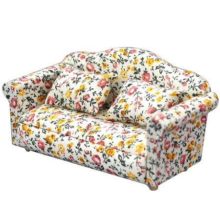 a white and yellow flowered couch with four pillows on top of the backrest