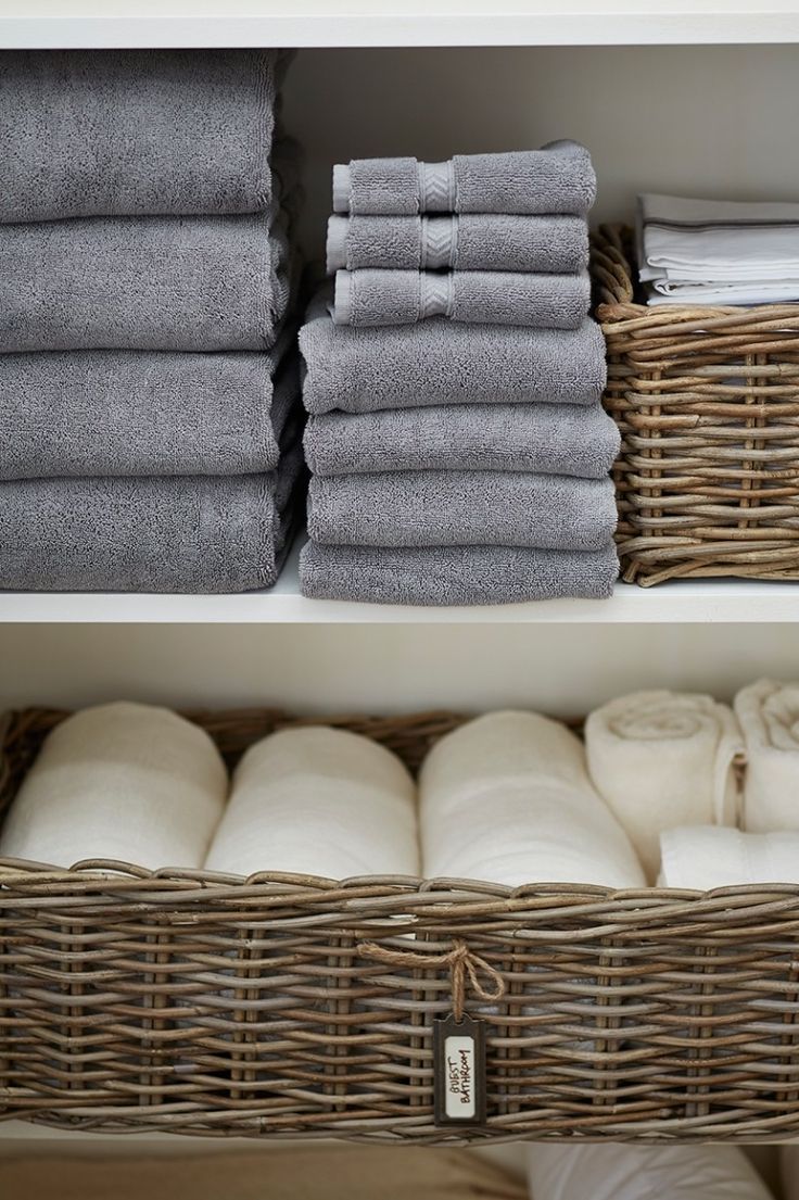 two baskets filled with towels next to each other on top of a white shelf in a closet