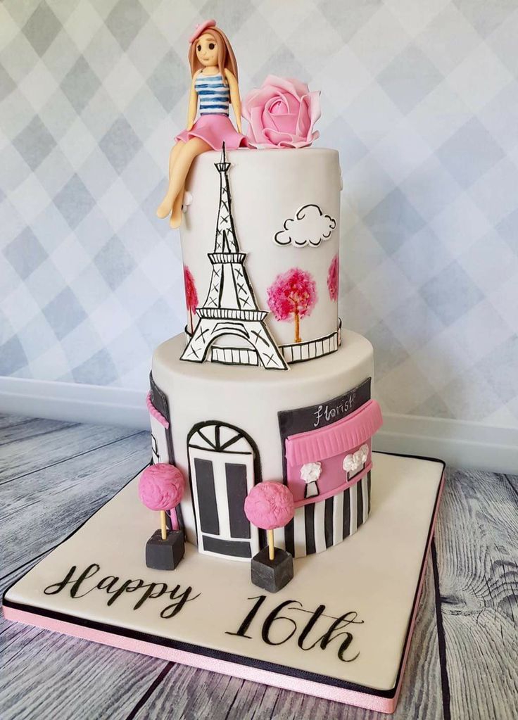 a birthday cake with the eiffel tower on top and pink flowers in front