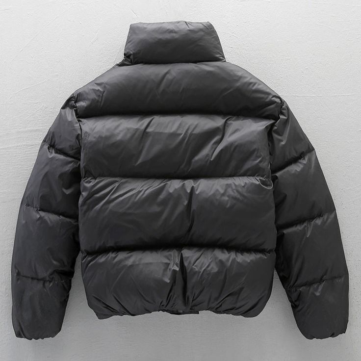 a black jacket hanging up against a white wall with the back turned to show it's hood