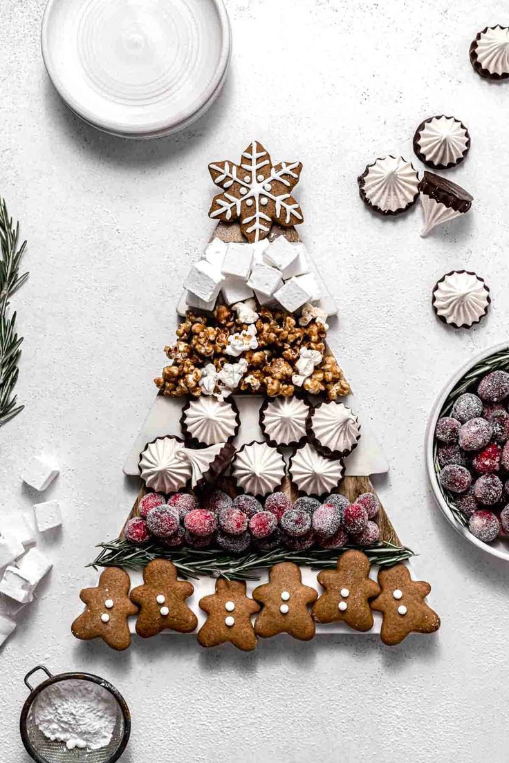 a christmas tree made out of cookies next to other holiday treats on a white table