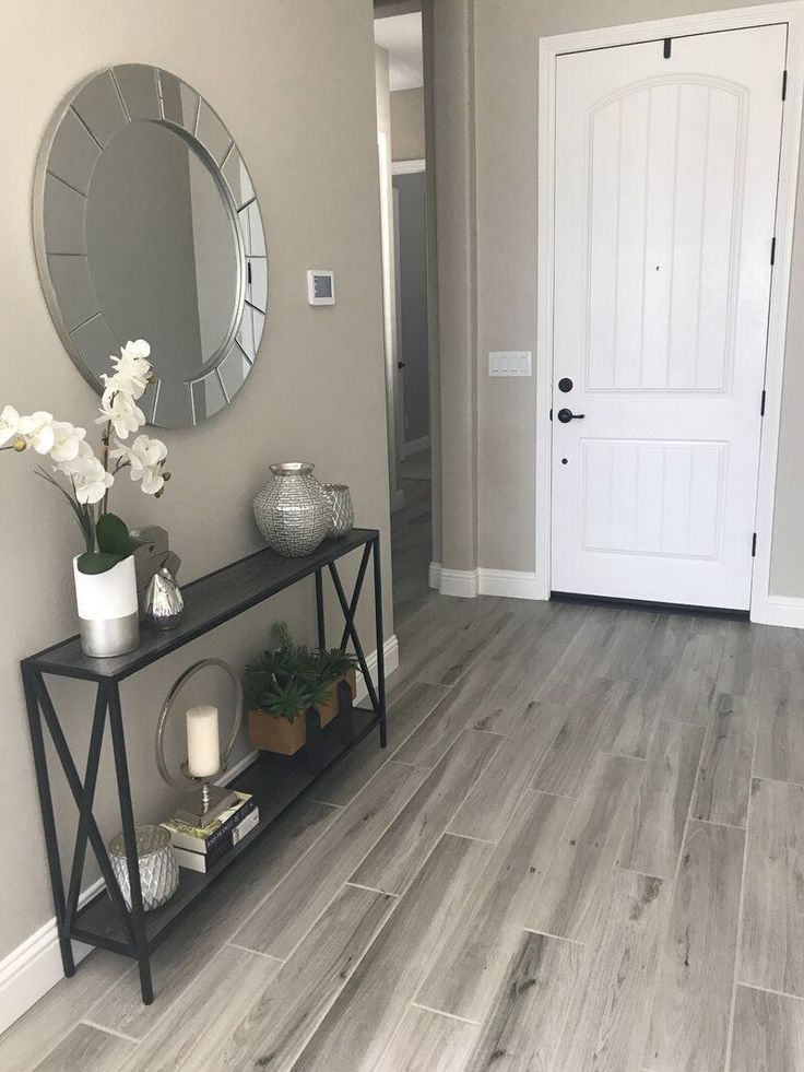 a room with a mirror, vases and flowers on a shelf in front of the door