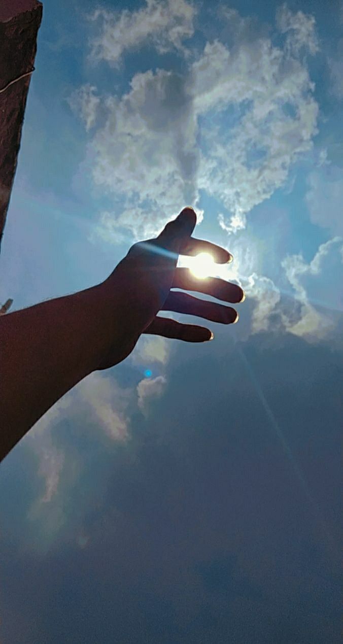 a person's hand reaching up into the sky