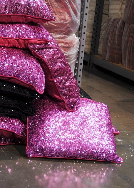 a pile of purple sequin pillows sitting on top of each other in a warehouse