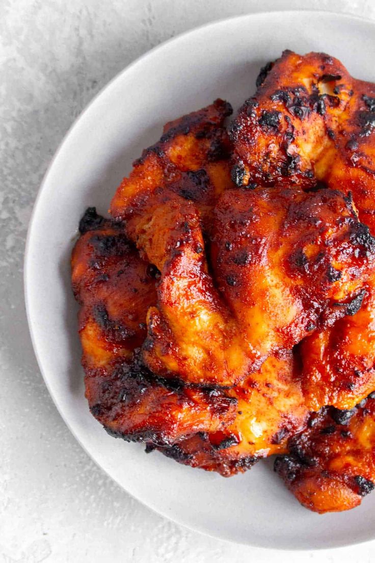 a white bowl filled with chicken wings on top of a table next to a fork