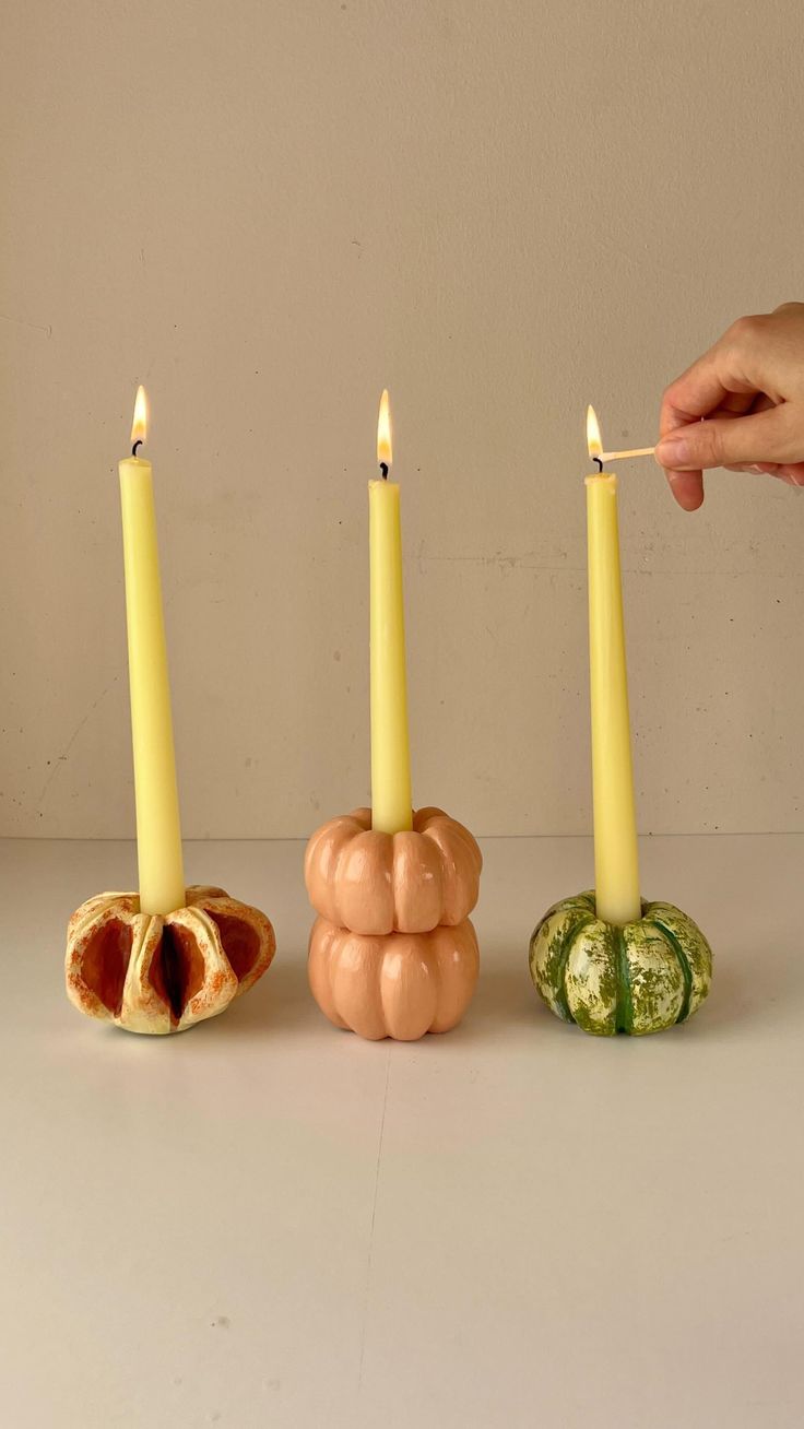 a person lighting candles in the shape of pumpkins and gourds