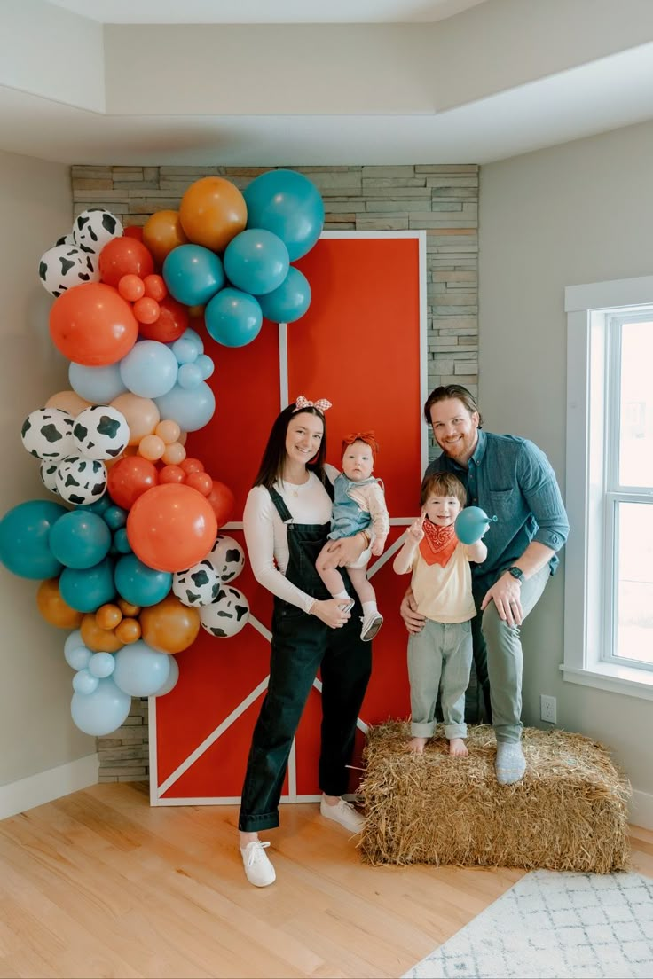 a family poses in front of a balloon wall