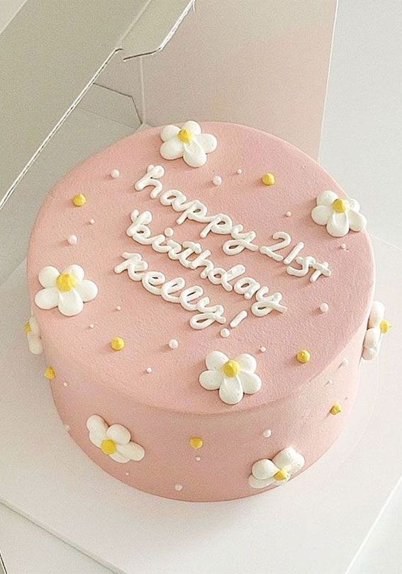 a pink birthday cake sitting on top of a white table next to an open box