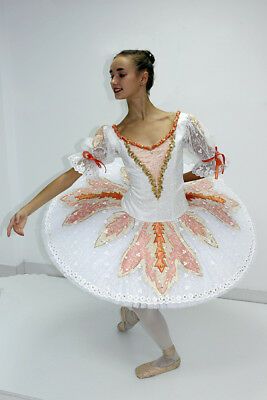 a woman in a white and orange dress is standing with her arms spread out to the side