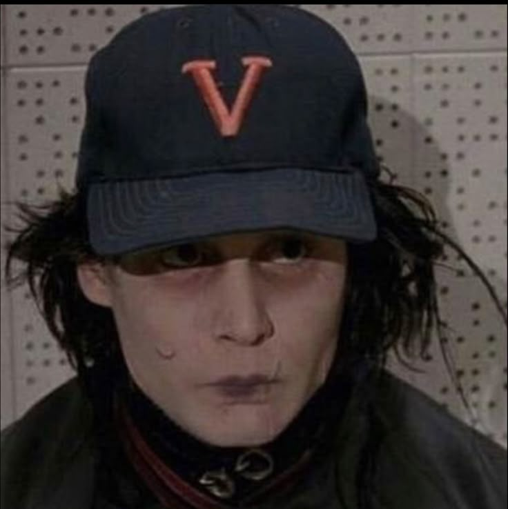 a man wearing a hat with the v on it's side and his face painted red