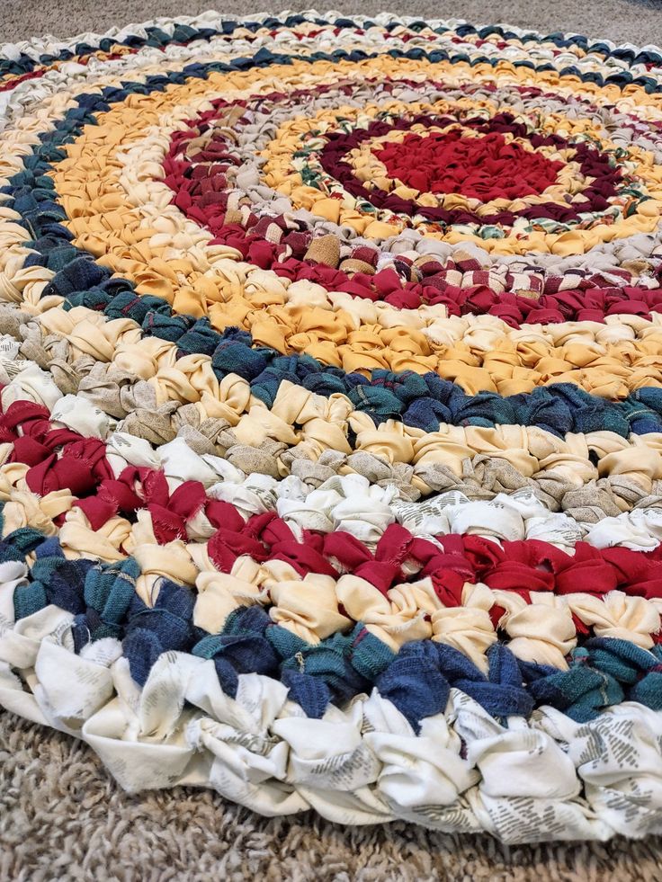 a multicolored round rug on the floor with white, red, yellow and blue colors