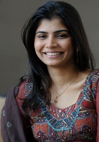 a woman with long black hair wearing a red and blue dress smiling at the camera