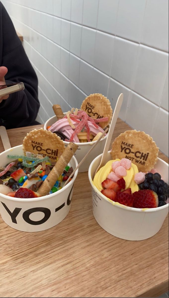 two buckets filled with different types of food on top of a wooden table next to a person holding a cell phone