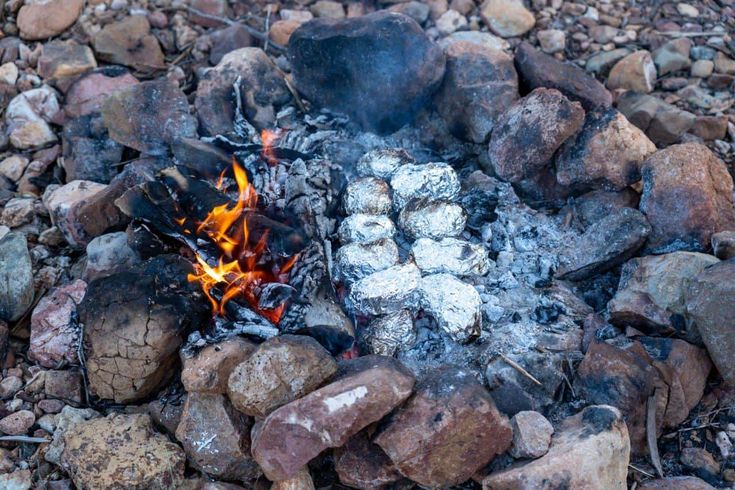 there is a fire burning in the middle of rocks and gravel on the ground with it's bright orange flames