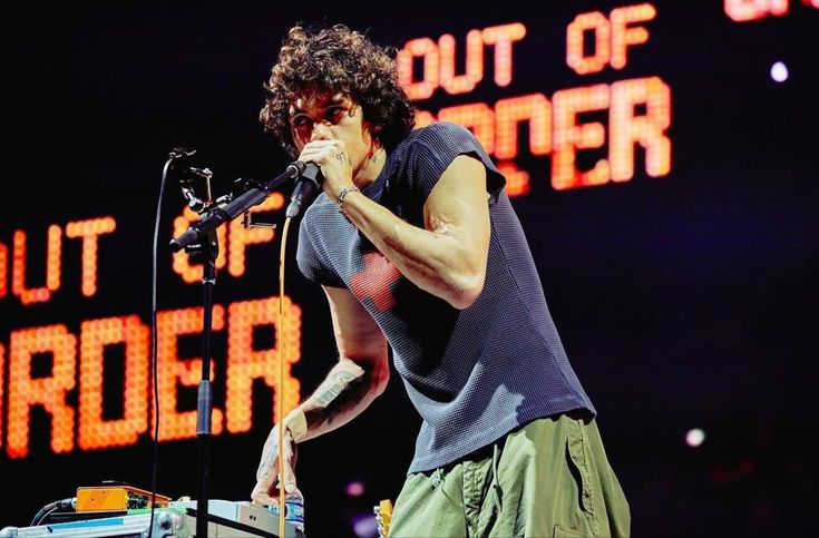 a man standing on top of a stage holding a microphone to his mouth and singing