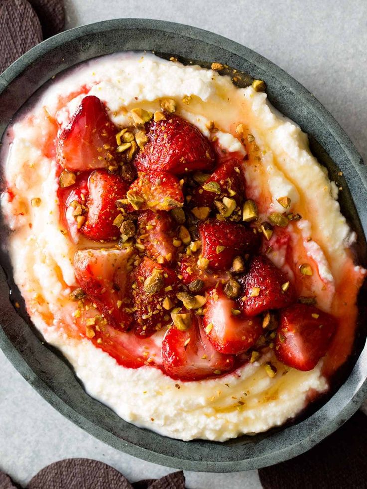 a bowl filled with mashed potatoes topped with strawberries and pistachios