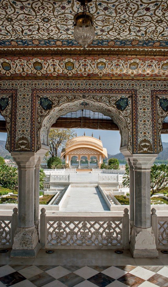 an intricately decorated building with columns and arches in front of the entrance to a garden