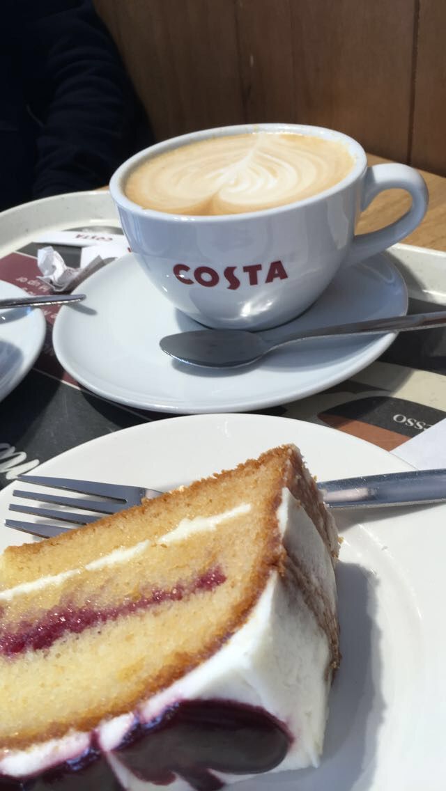 a piece of cake sitting on top of a white plate next to a cup of coffee