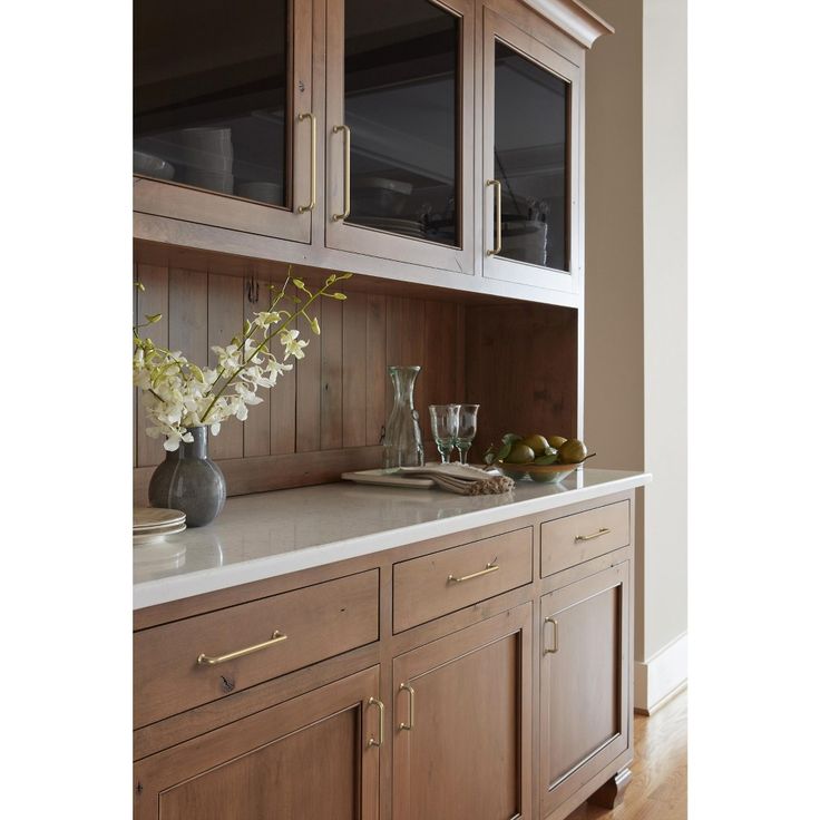 a kitchen with wooden cabinets and marble counter tops, along with vases filled with flowers