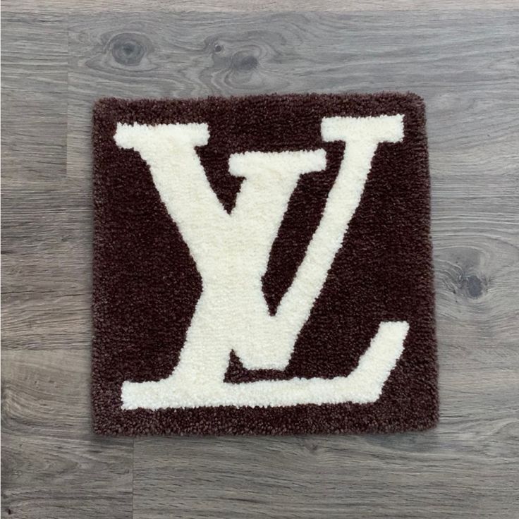 a brown and white rug with the letter l on it in front of a wooden floor